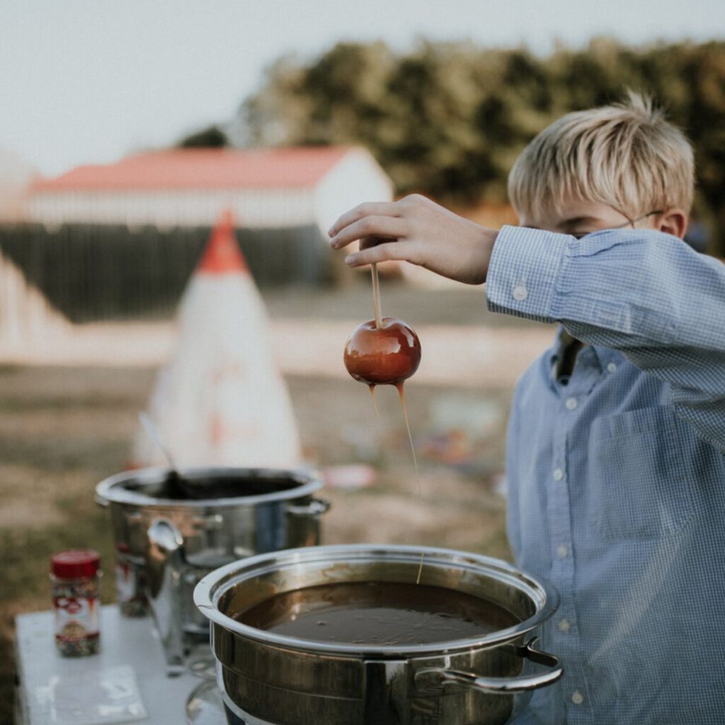 boy holding up a caramel apple station