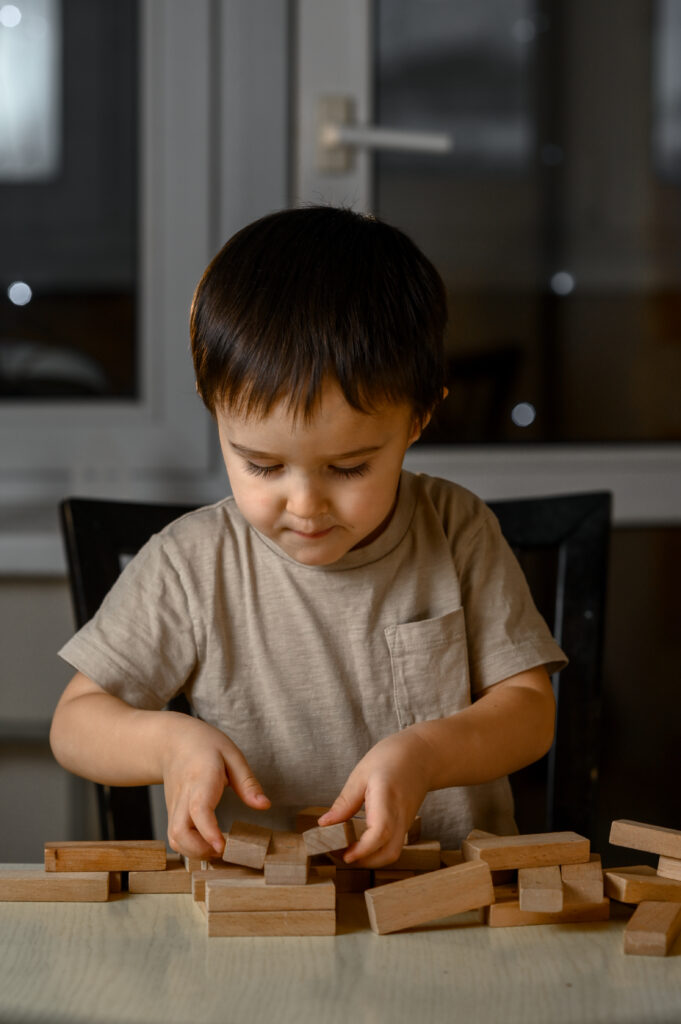 little boy playing with wooden blocks on a table