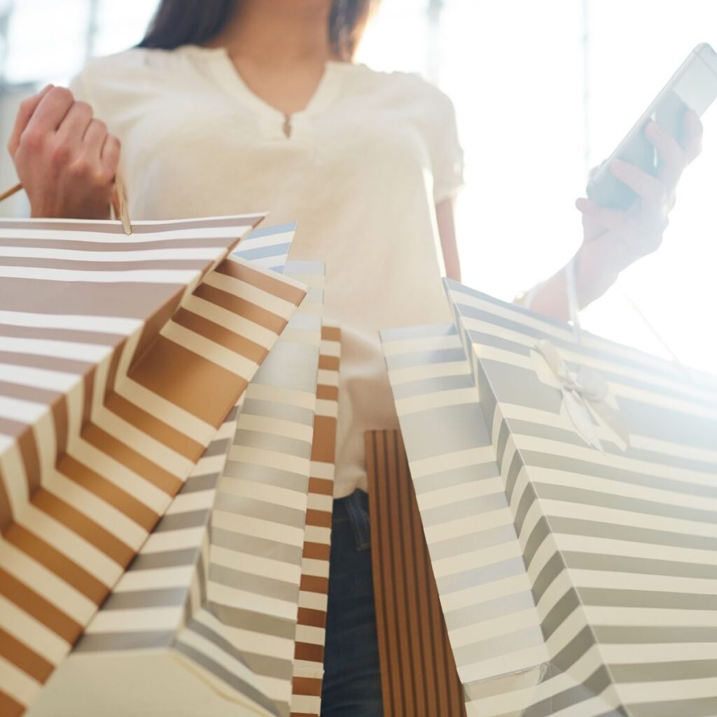 woman holding several shopping bags and her cell phone