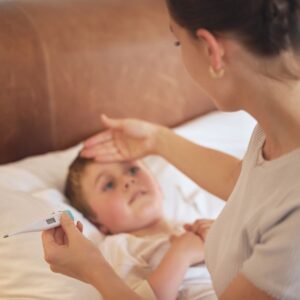 Mother holding a thermometer checking her sick son's temperature