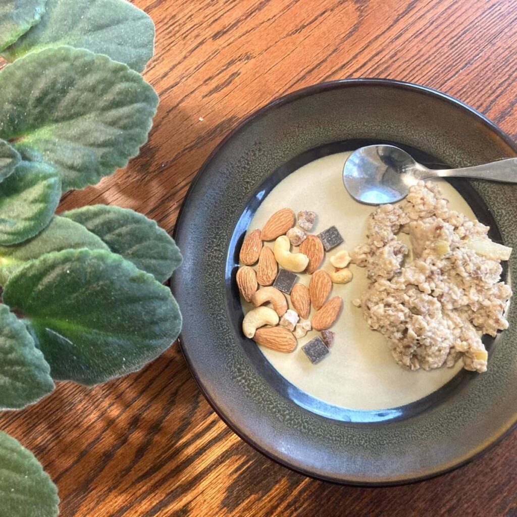 Plate with trail mix and oatmeal on it sitting on table with small spoon 