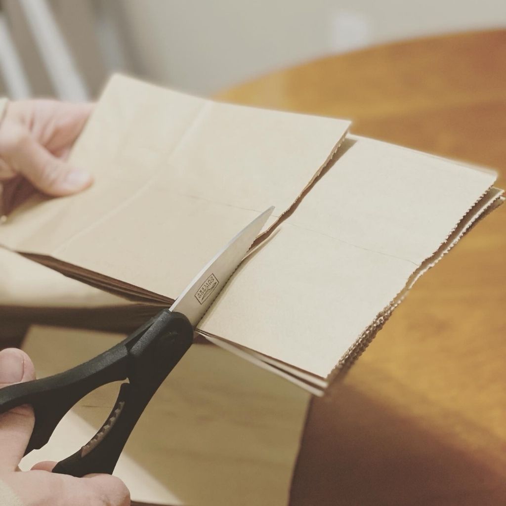 person using scissors to cut brown paper bags