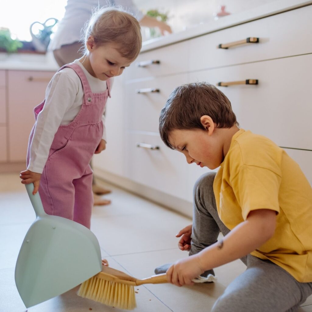 little boy and girl helping to clean house using small dust pan and brush