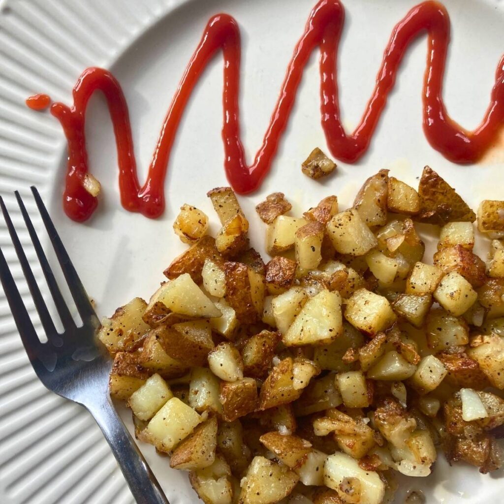 southern fried potatoes on a plate with a fork and ketchup