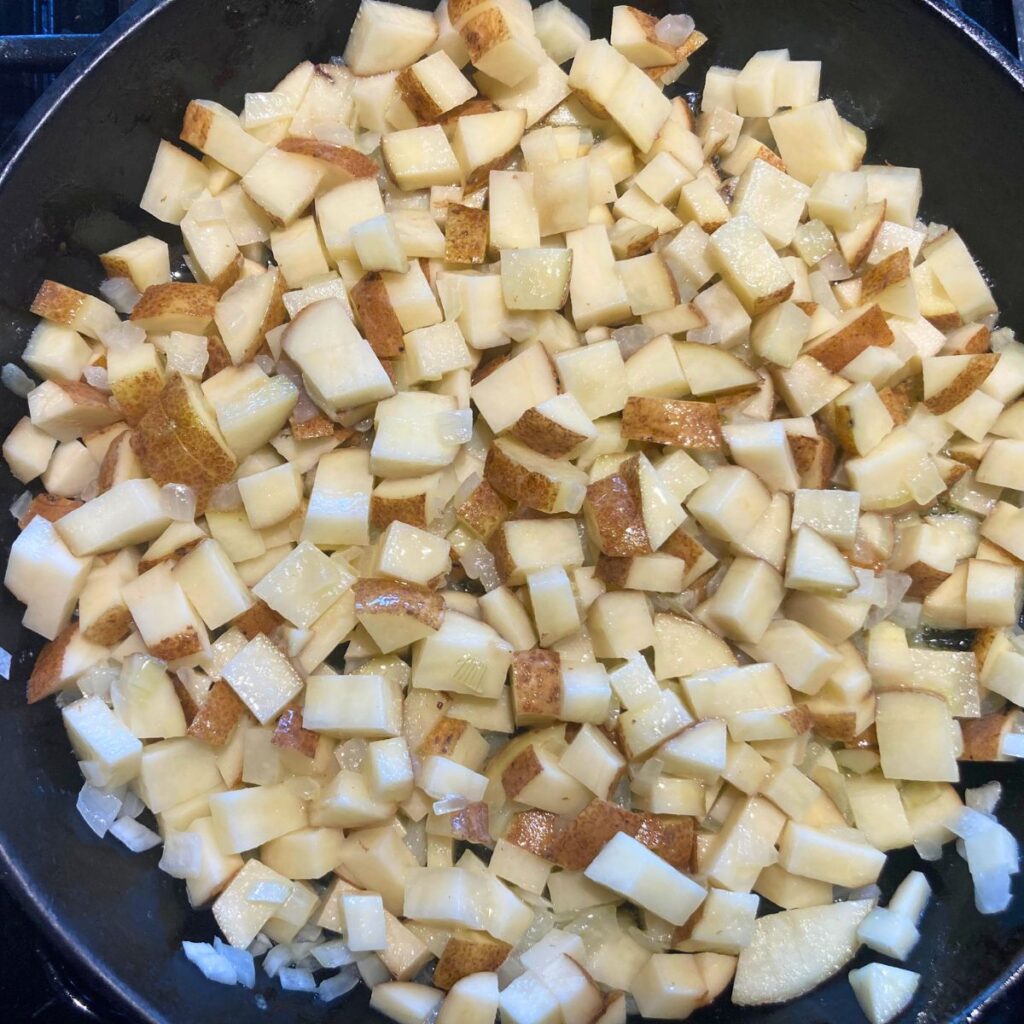 potatoes frying in a cast iron skillet