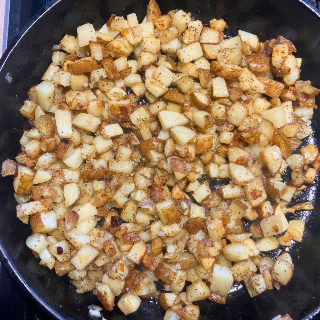 crispy potatoes frying in a cast iron skillet