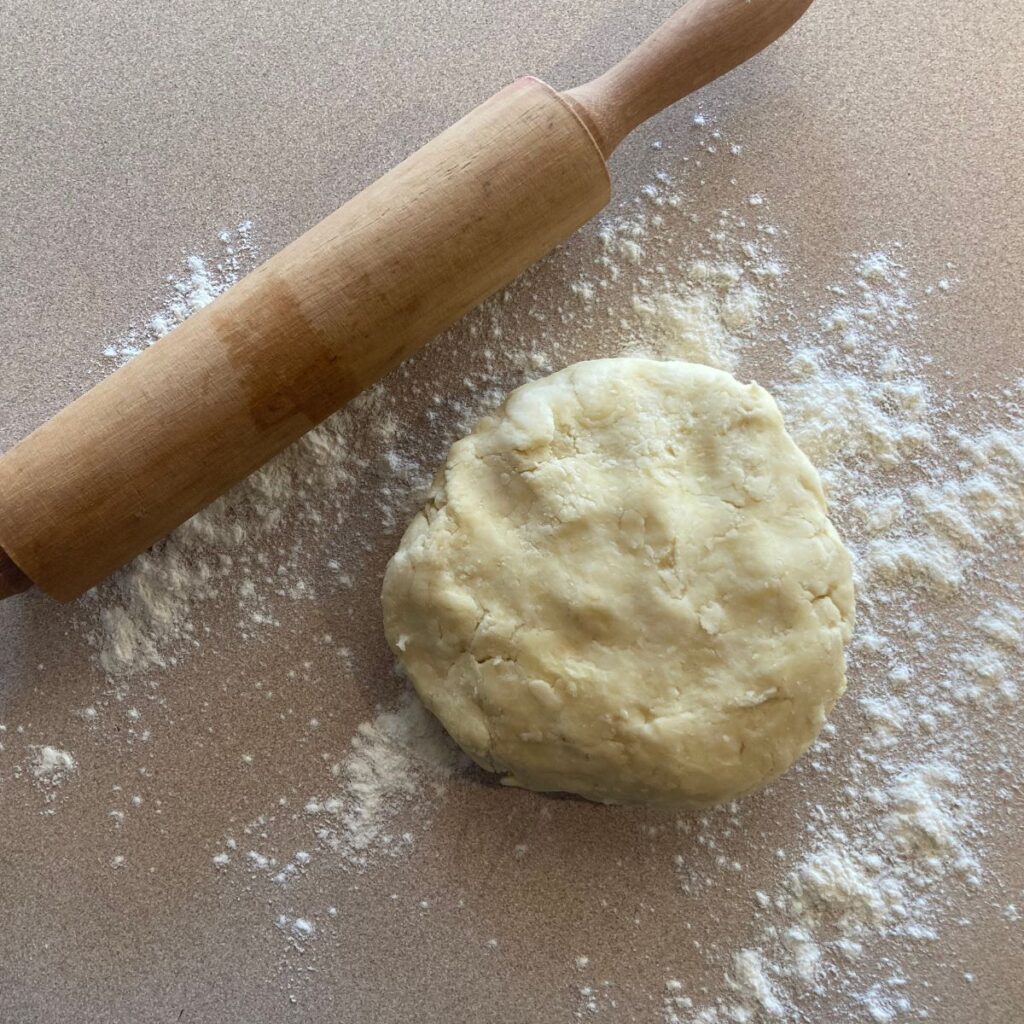 top down photo of pie dough on a lightly floured surface with a rolling pin
